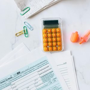 A flat lay image of tax forms, calculator, and office supplies on a desk.
